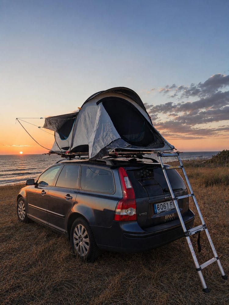 Eine Plat4tent-Plattform und ein Dachzelt aufgebaut auf einem Auto am Meer bei Sonnenuntergang an der baskischen Küste