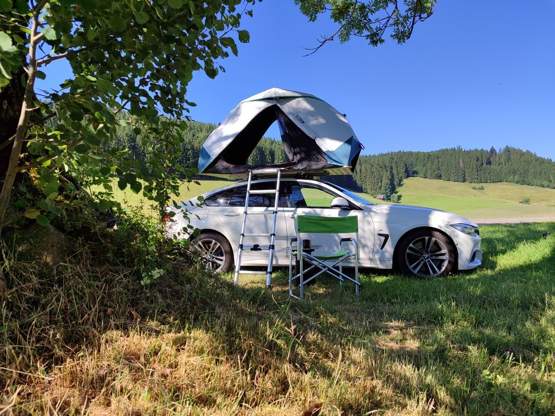 Ein Auto mit dem Zelt aufgebaut auf dem Dach, eingerichtet als Camping-Basis auf dem Autodach